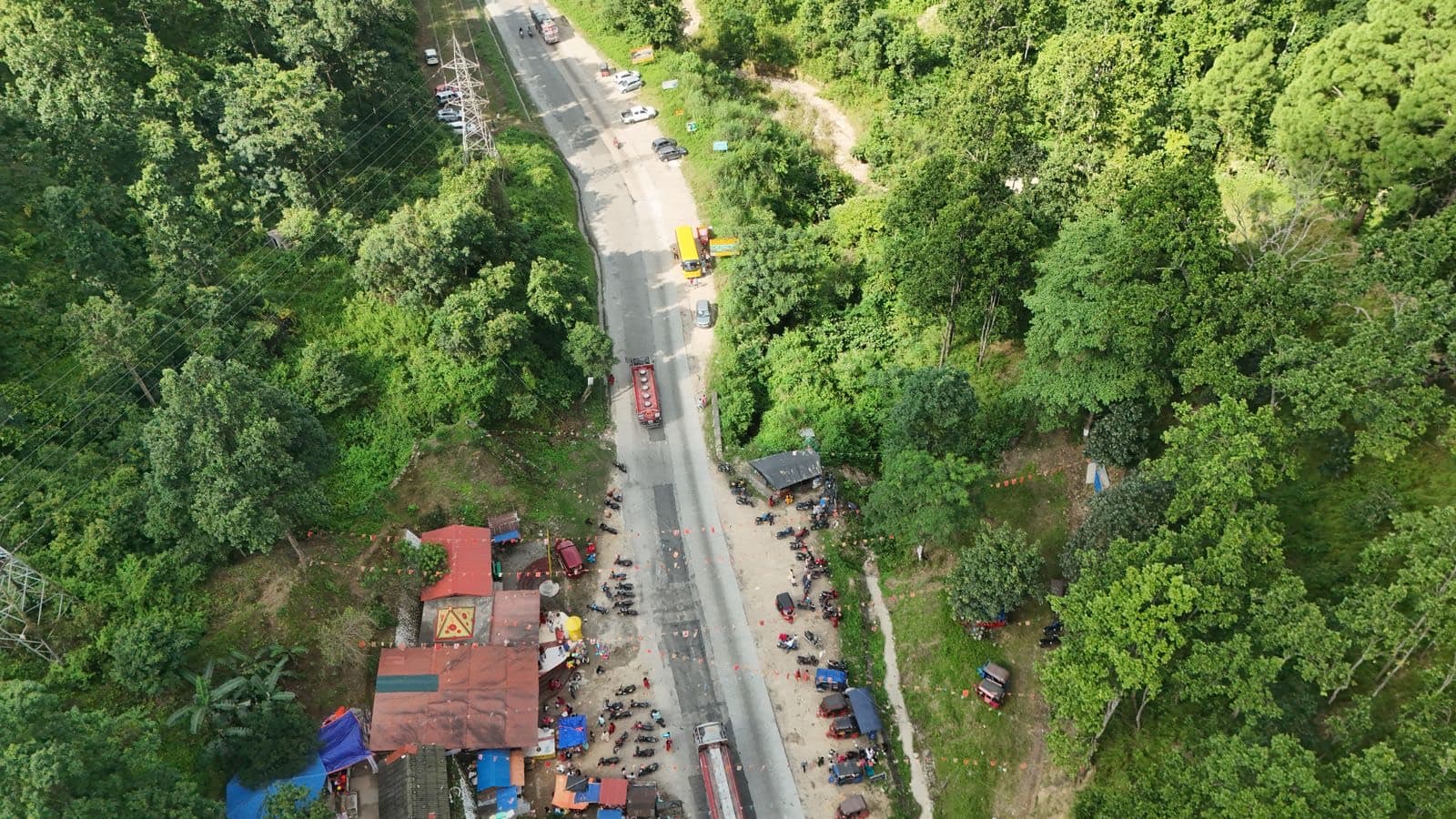 Aerial view of a Nepali highway lined with shops and green forest