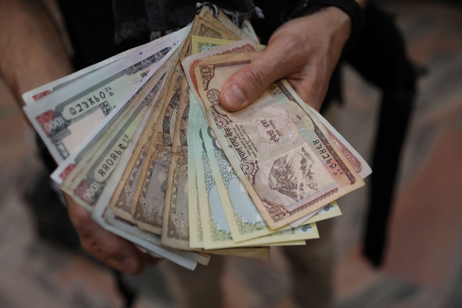 Hand holding a fan of Nepali rupee notes